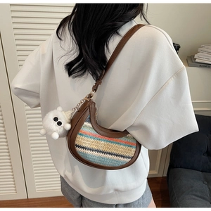 Detail of colorful striped woven crossbody bag with brown leather trim and plush charm