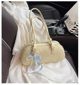 Dettaglio di una borsa Boston beige crema con ciondolo di perle su sedile d'auto