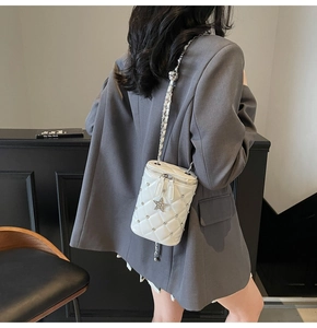 Sac seau blanc matelassé avec rivets et breloque étoile porté par un mannequin femme