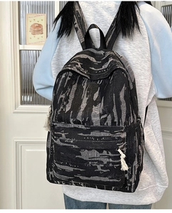 Detail of black and gray jacquard backpack with fringe tassel and textured denim fabric