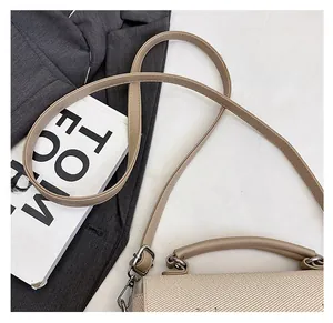 Close-up of woven shoulder bag strap with silver metal buckle and textured material