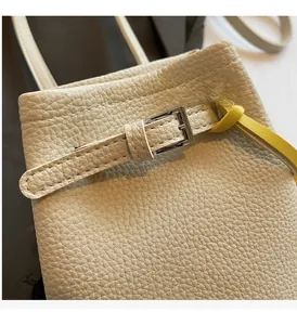 Close-up of litchi grain leather bucket bag with silver buckle and yellow accent strap