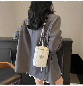 Détail du sac seau blanc matelassé avec accents de strass et pendentif étoile argenté