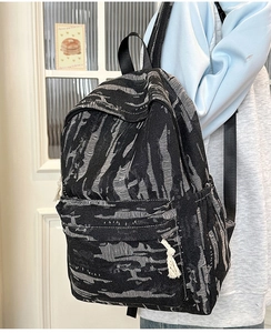 Detail of large denim backpack with unique distressed texture and drawstring side pockets