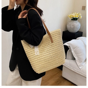 Straw tote bag with brown leather straps and white lace bow shown in a home setting