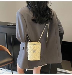 Détail du sac boîte jaune matelassé avec strass brillants et breloque étoile sur chaîne