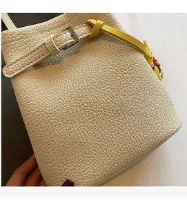 Detailed macro view of off-white lychee pattern leather bucket bag with decorative buckle