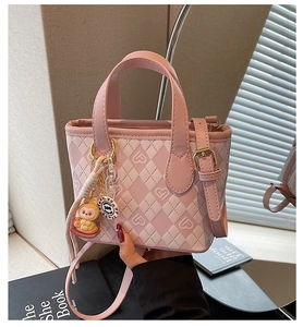 Borsa a secchiello trapuntata rosa con stampe a cuore e ciondolo a coniglio portata a mano