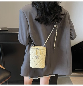 Gros plan sur le sac seau matelassé crème avec pendentif étoile et bandoulière en chaîne