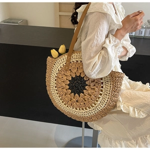 Detail view of woven paper straw beach bag with circular pattern and leather shoulder strap