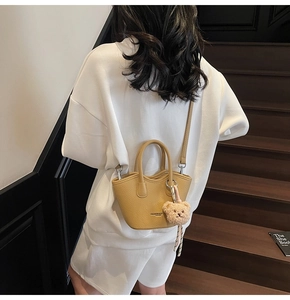 Détail du sac seau en cuir jaune moutarde avec grain litchi et breloque ours mignon