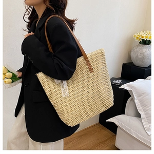 Detail of the woven tote bag showing white lace bow and brown leather shoulder strap