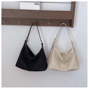 Detail view of large tote bags in black and beige leather with zip and metal buckle