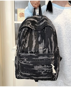 Detail of vintage denim backpack showing distressed fabric texture and woven zipper puller