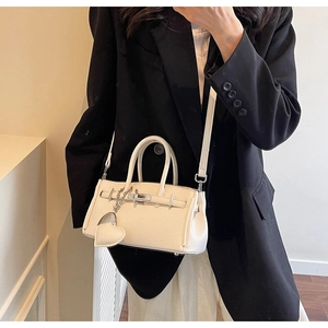 Dettaglio borsa a mano in pelle martellata bianco sporco con chiusura argento e cuore