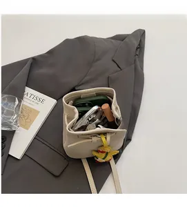 Detail view of cream bucket bag showing interior capacity with phone and cute duck charm