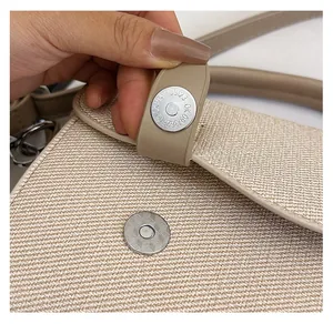 Close-up of durable silver magnetic buckle and woven texture on beige crossbody bag