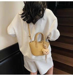 Détail du sac seau jaune texturé litchi avec breloque ours et gaufrage de mode