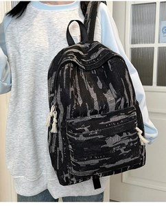Close-up of black and grey marble denim backpack with white decorative rope zipper pulls