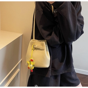 Detail of light yellow bucket bag with lychee texture and yellow duck charm