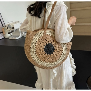 Fashionable gradient round straw beach bag worn by a model in a cozy indoor setting