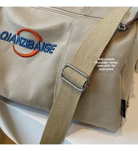 Détail de la bandoulière réglable tissée avec boucle métallique sur un sac en toile beige