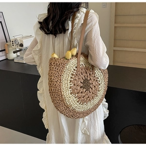 Detailed close-up of a tricolor woven straw shoulder bag with leather straps and round pattern