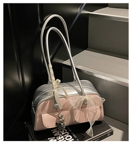 Detail of silver and dusty pink saddle bag with lace bow and heart-shaped metal charms