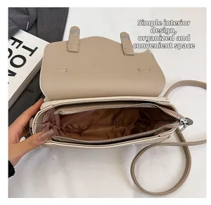 Detail view of beige crossbody bag showing secure zipper closure and spacious interior lining