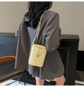 Détail du sac seau matelassé jaune crème avec pendentifs étoile et bandoulière chaîne