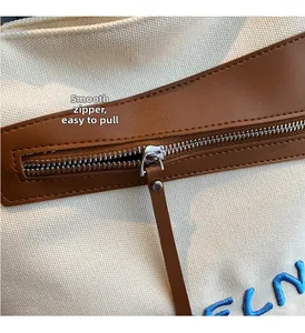 Détail de la fermeture éclair fluide et de la longue tirette en cuir marron sur le sac