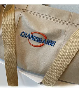 Gros plan sur la texture de toile beige et la broderie de qualité sur le sac cabas
