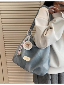 Sac cabas en jean bleu avec pendentif capybara porté par un mannequin à l'épaule