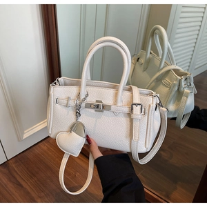Dettaglio della borsa in pelle bianca a grana con ciondolo a cuore riflesso nello specchio