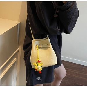 Beige lychee pattern bucket bag with a cute yellow duck charm and thin shoulder strap