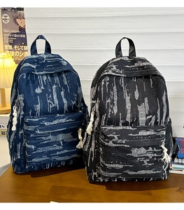 Detail of vintage denim backpacks with tie-dye texture and woven cotton rope tassels