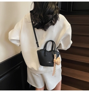 Détail du sac seau noir en cuir synthétique avec breloque d'ours et bandoulière réglable
