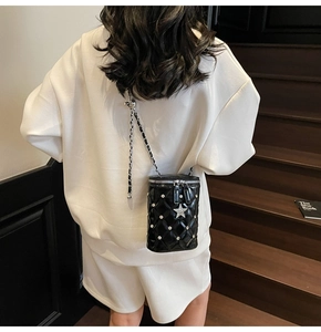 Détail d'un sac seau matelassé noir avec étoiles argentées et bandoulière en chaîne