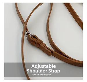 Macro view of adjustable brown leather shoulder strap with silver buckle and fine stitching