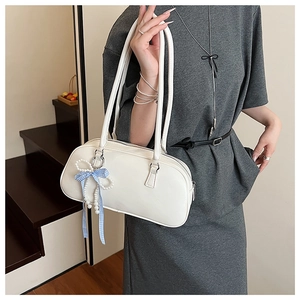 Dettaglio della borsa in pelle bianca con ciondolo di perle e fiocco a quadretti blu
