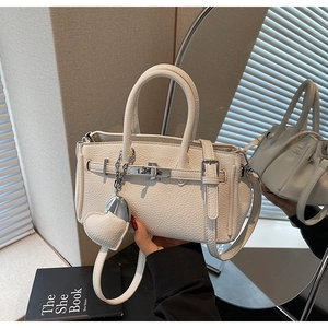 Dettaglio di una mini borsa in pelle crema con ciondolo a cuore e finiture argentate