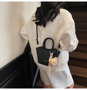 Détail du sac cabas en cuir grainé noir avec texte et breloque ours en peluche