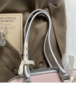 Detail of pink satin saddle bag with silver handles and elegant cream ribbon bow