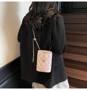 Sac seau matelassé rose avec bandoulière chaîne et étoile en strass porté par un mannequin
