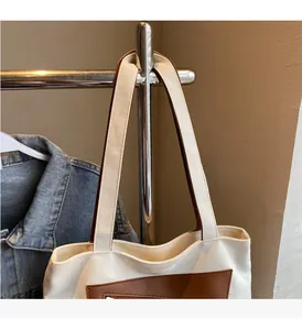 Détail du sac fourre-tout en toile avec anses en cuir marron et coutures robustes