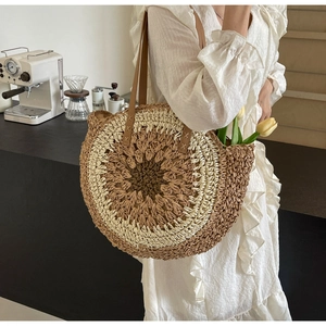 Detail of woven straw shoulder bag featuring tri-color concentric circles and leather handles