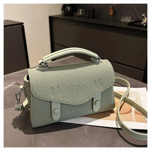 Macro view of light green crossbody bag showing woven texture and decorative buckle detail