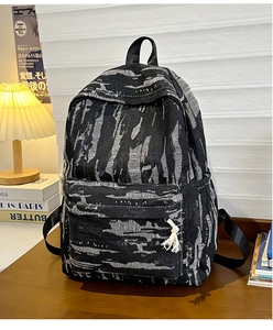 Detailed view of large denim backpack with gray camouflage texture and tassel zipper pull