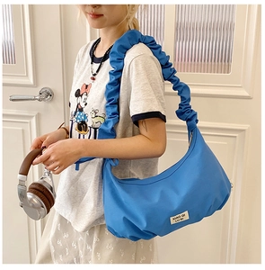 Blaue Falten-Beuteltasche getragen vom Modell, im lässigen Schultertaschen-Stil