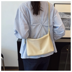 Detail of cream minimalist tote bag with adjustable strap worn over striped shirt
